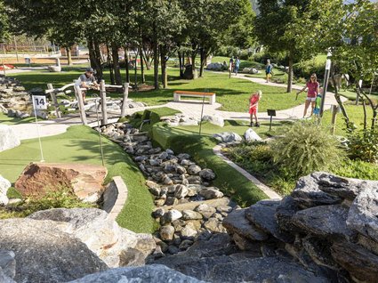 Dein Apartment im Zillertal in bester Lage Menschen spielen Minigolf in einem sonnigen Park mit Bäumen und Felsen