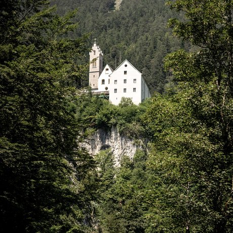 Sommer im Zillertal für die ganze Familie Weißes Schloss auf Felsen umgeben von dichtem grünen Wald und Bergen