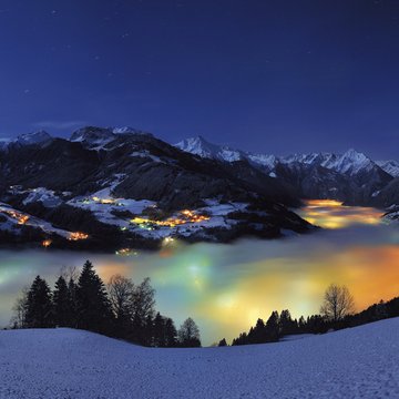Your accommodation in Zillertal for holidays with friends Night view of snowy valley with fog and colorful lights in the Alps