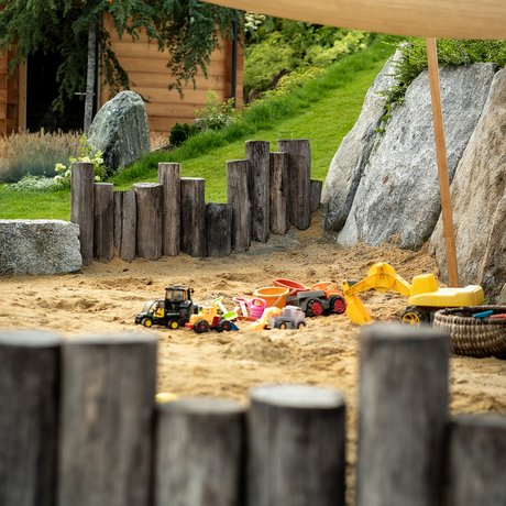 Sommer im Zillertal für die ganze Familie Kindersandkasten mit Spielzeugbagger und Holzumrandung im Garten